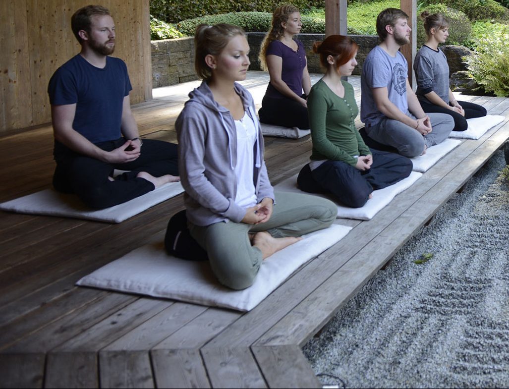 junge Menschen der Generation Zukunft meditieren im Zen Garteb