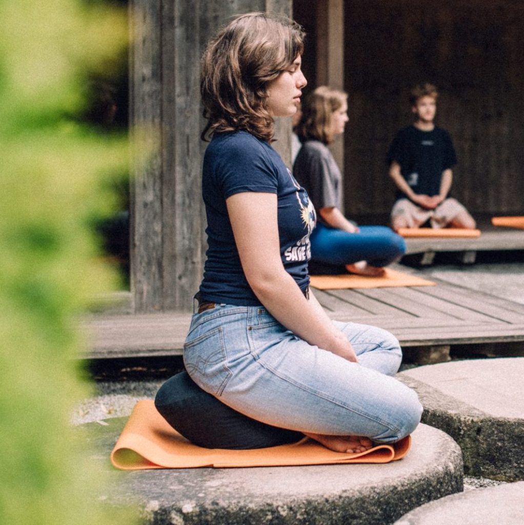 Junge Menschen meditieren im Zen-Garten